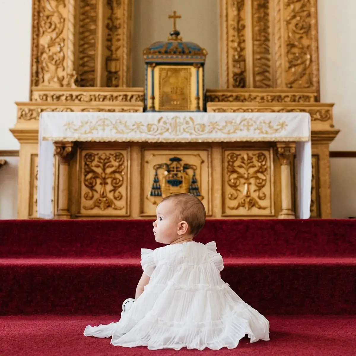 Fotografo per battesimi a Genova: bambina in abito bianco seduta davanti all'altare della chiesa