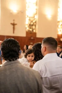 Bambina in abito di pizzo si volta verso l'obiettivo tra gli invitati durante un battesimo in Liguria